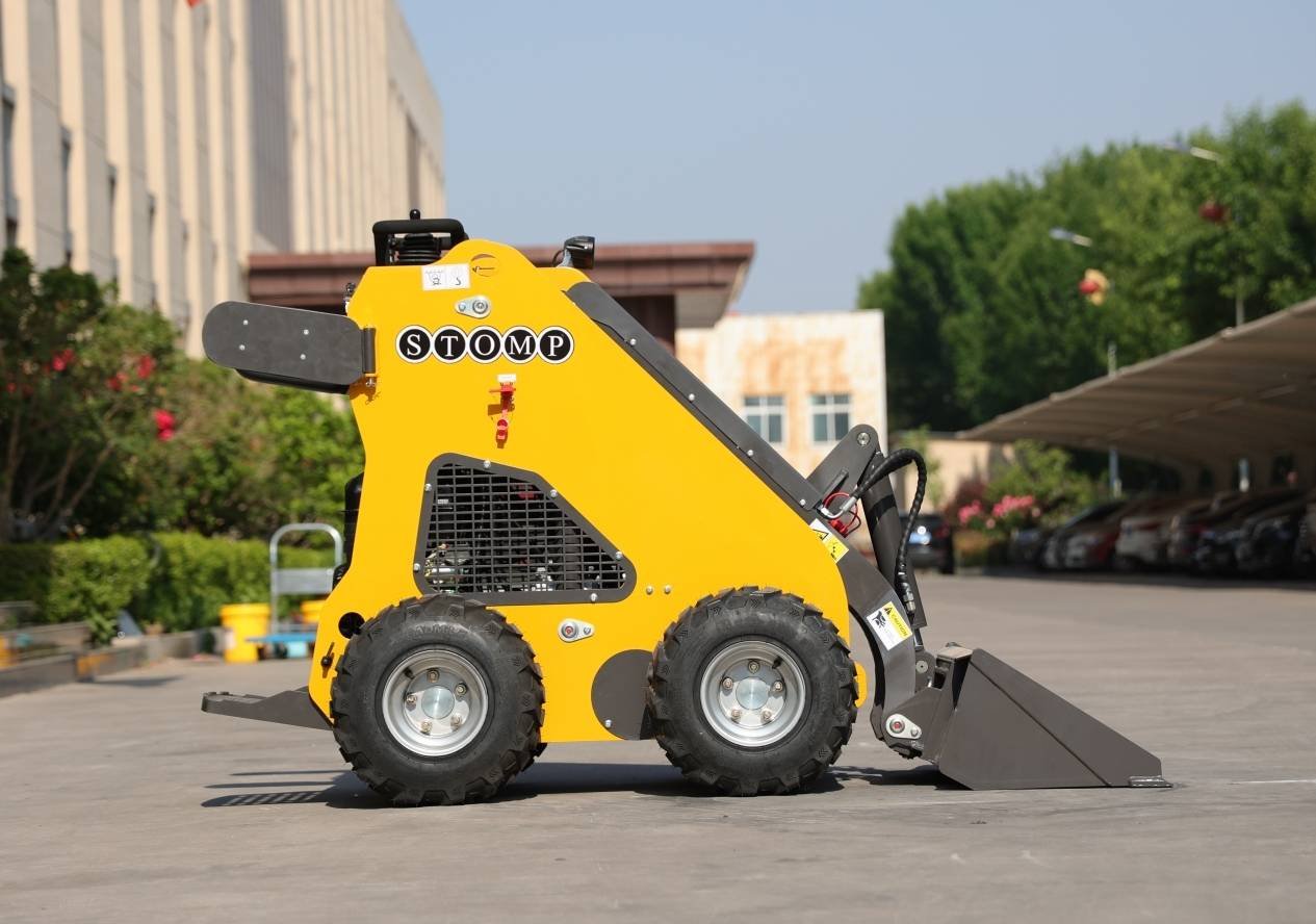 Yellow compact skid-steer loader with a front bucket on a paved lot