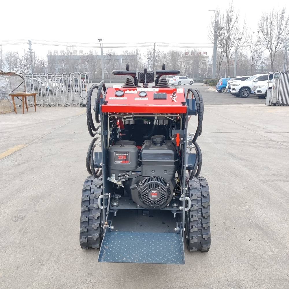 Rear view of a compact tracked utility vehicle with a metal loading ramp, exposed engine, and control handles for construction use.