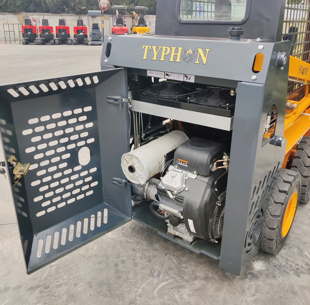 Open engine compartment of a grey Typhon heavy-duty machine showing the engine, exhaust wrap, and protective perforated door; yellow wheels visible in the background.