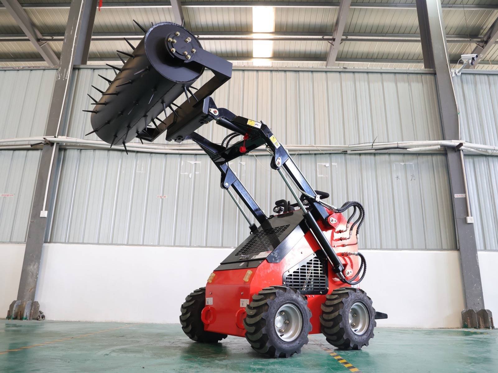 Red industrial stump grinder with a large, spiked rotating cutter wheel raised on a hydraulic arm inside a warehouse.