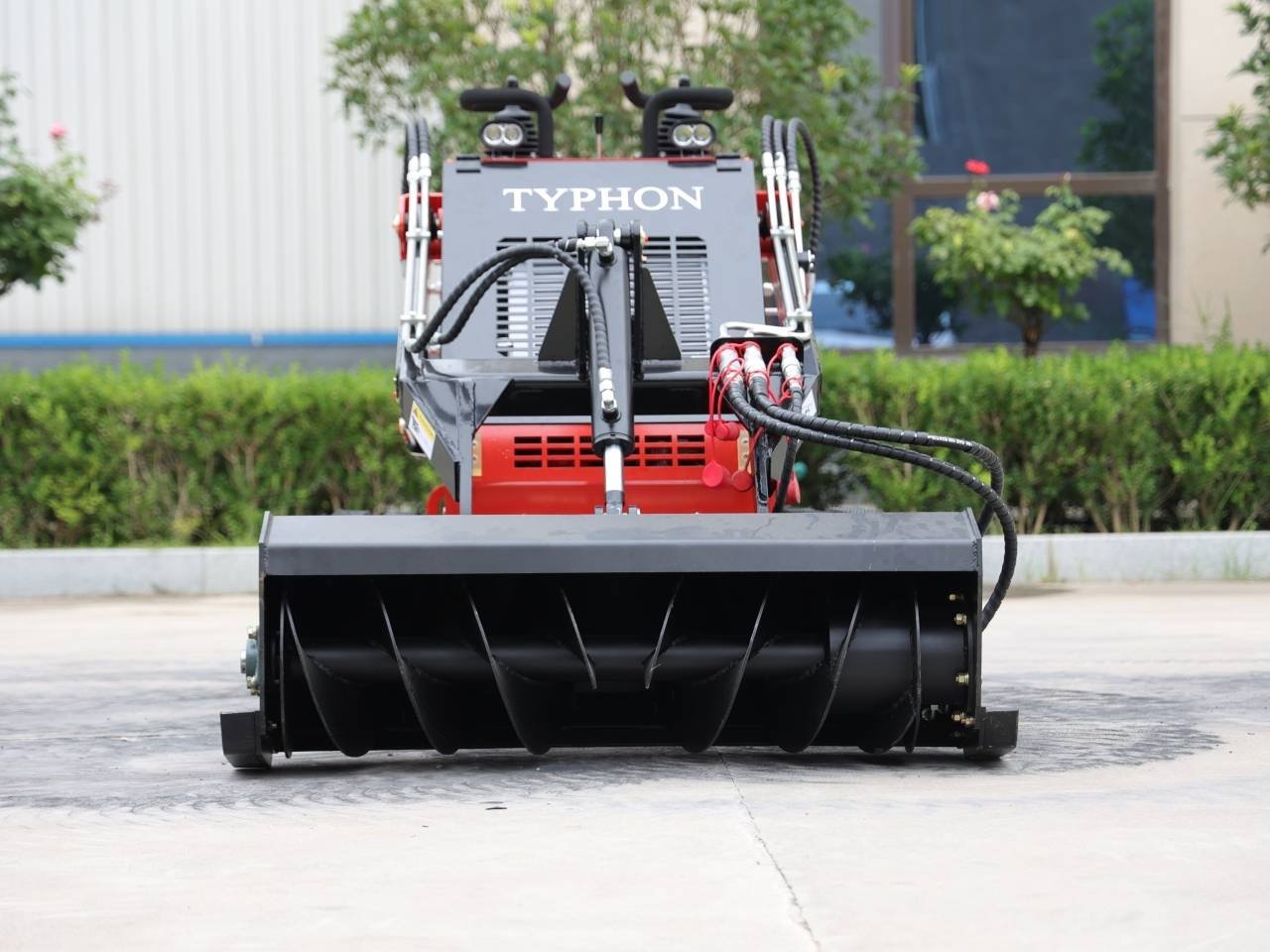 Front view of a Typhon heavy-duty machine with a large black ribbed roller attachment outdoors.