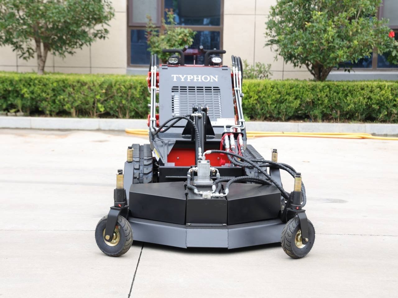 Front view of a Typhon soil/ asphalt compactor with hoses, wheels, and a large black base in an outdoor paved area.