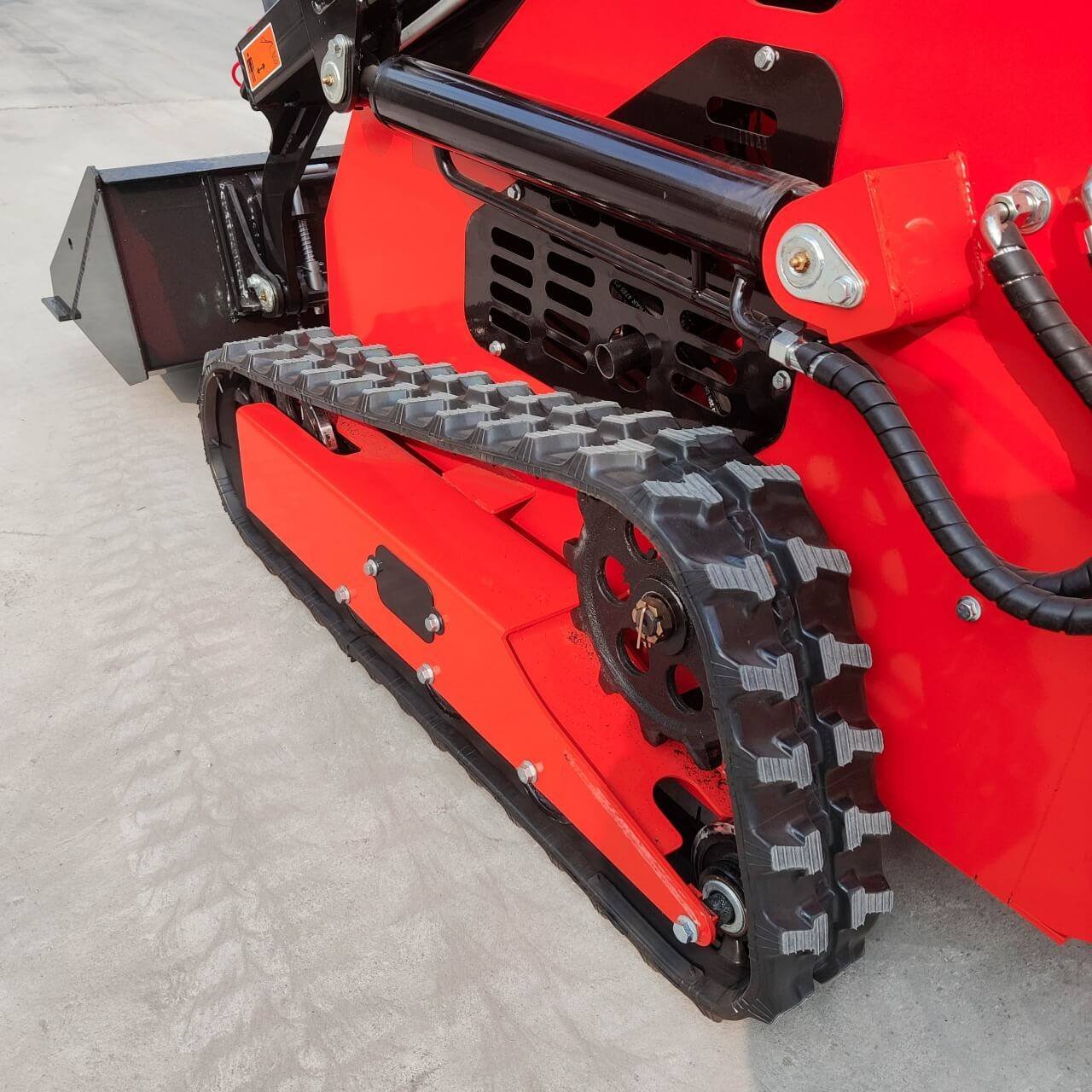 Close-up of a red tracked construction machine showing the rubber track and drive sprocket.
