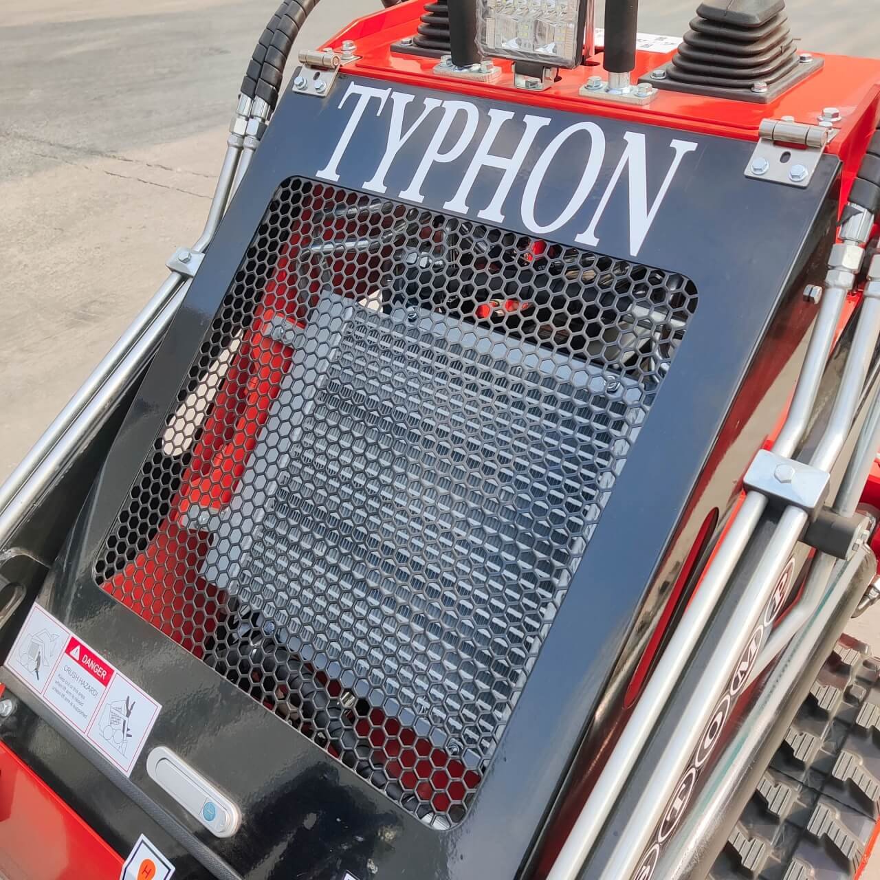 Front of a red heavy machinery with a hexagonal grille and the word TYTHON on the panel.